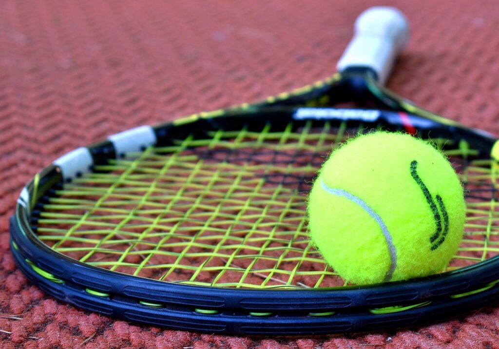 raquette de tennis posée sur le sol avec une balle placée sur le cordage